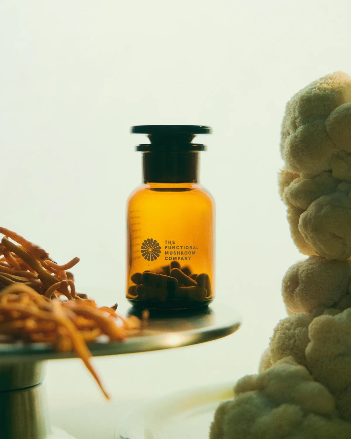 Orange bottle with black cap on a white surface, surrounded by dried herbs and a woven basket.