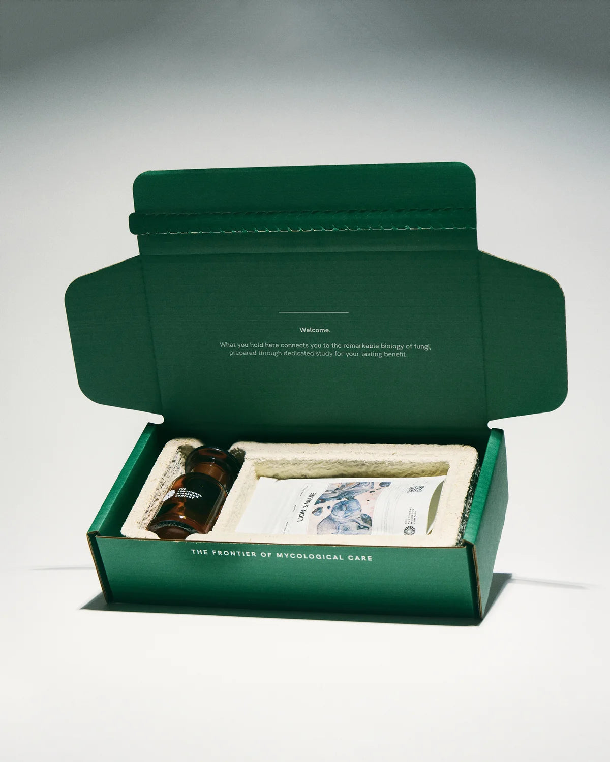 Green box with a small bottle and packaging on a white background