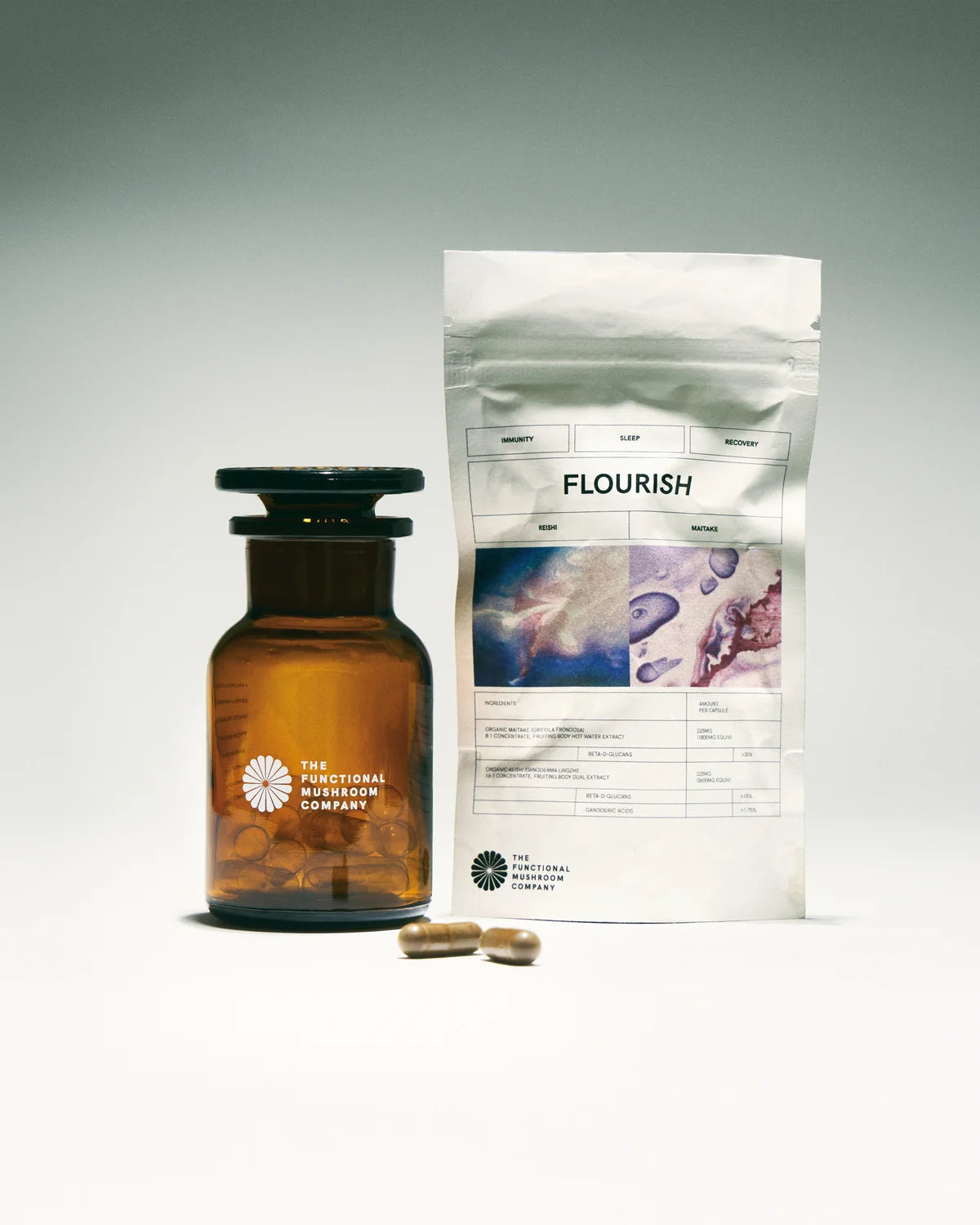 Brown glass bottle with black cap and white label, next to a white package labeled 'Flourish' on a gray background.