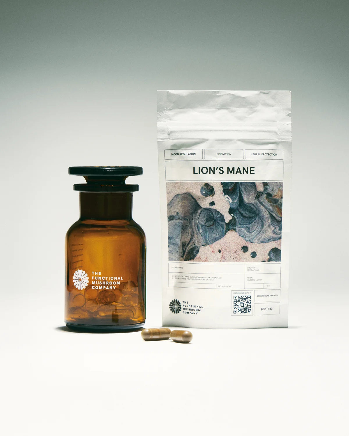 Amber glass bottle, packaging labeled 'Lion's Mane', and capsules on a gray background
