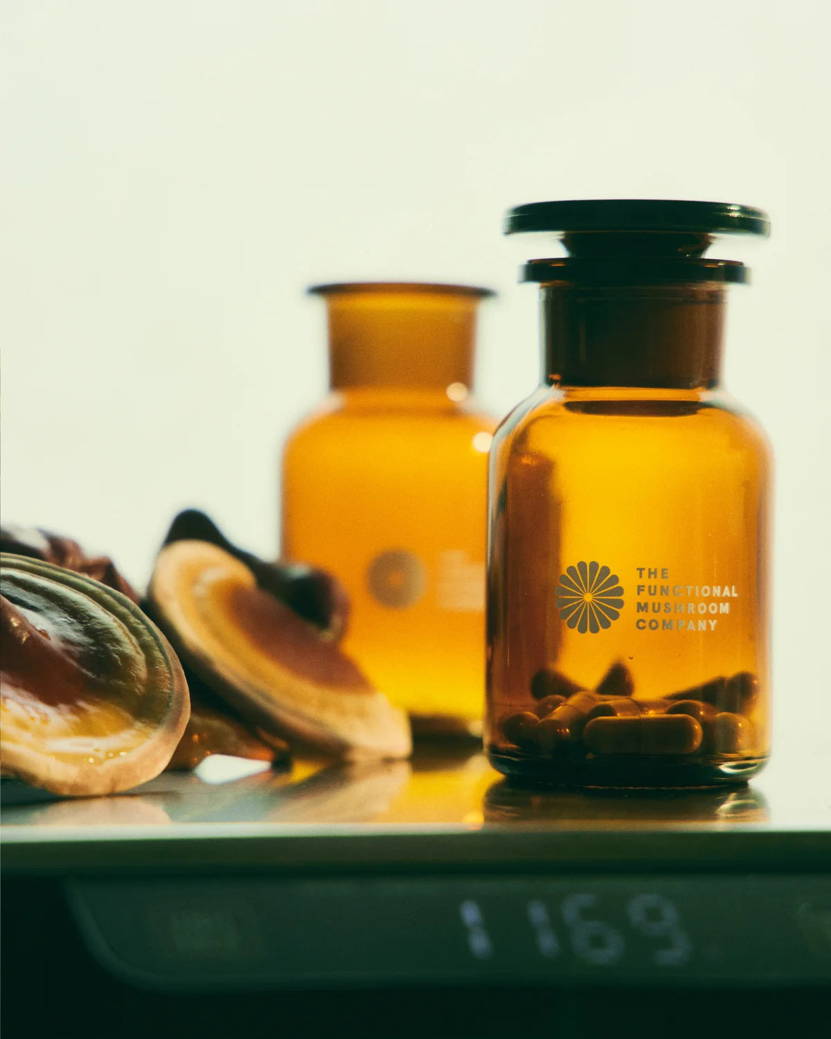 Two amber glass bottles with a logo on a reflective surface.