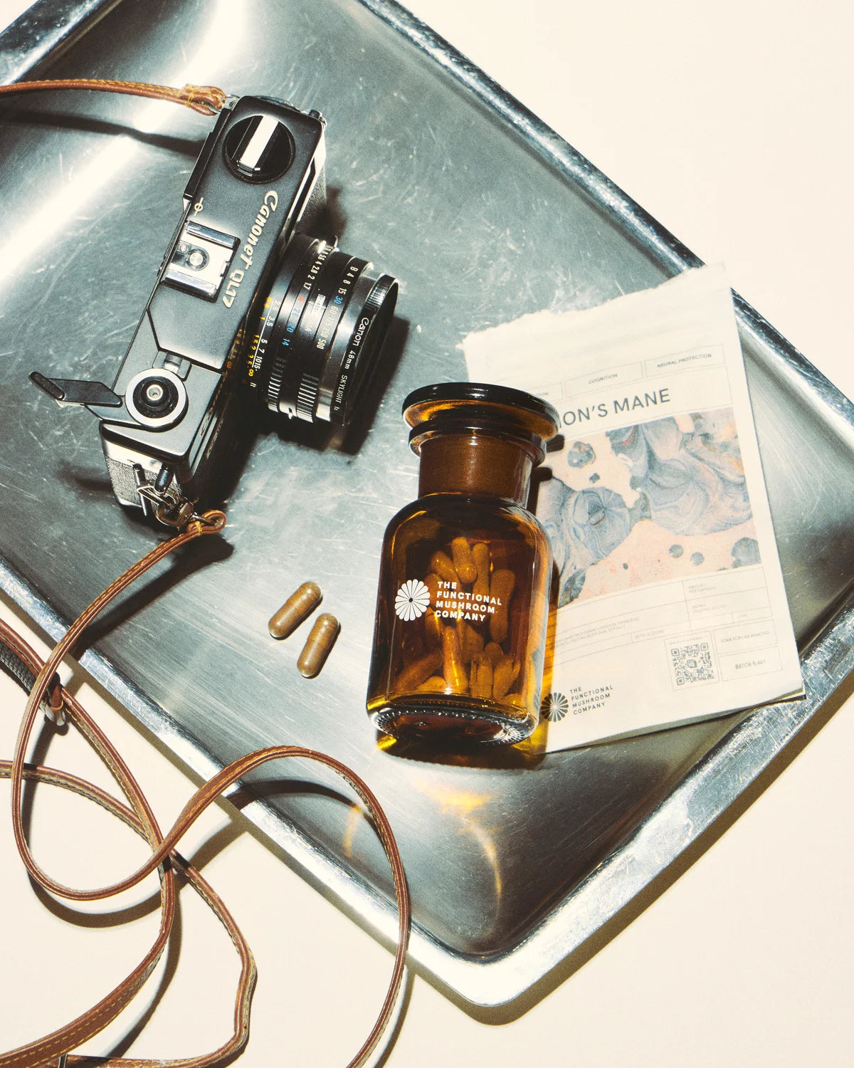 Vintage camera, brown bottle, and paper on a reflective surface