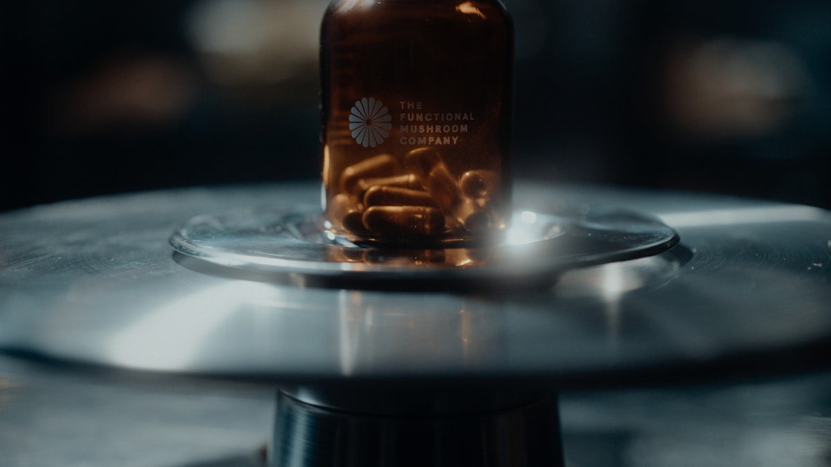 An amber Functional Mushroom Company jar of capsules on a steel turntable