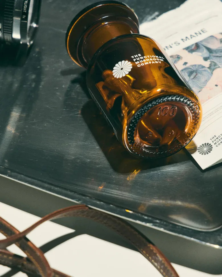 The Animate apothecary jar on a steel tray beside a vintage camera and a Lion's Mane pouch