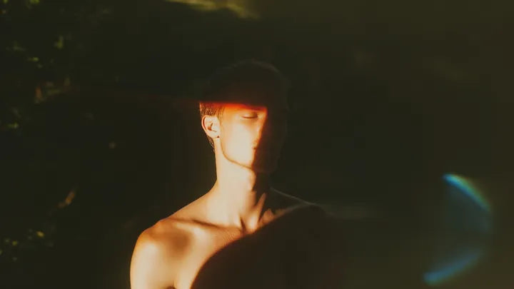 A person in low, warm side light with their eyes closed.